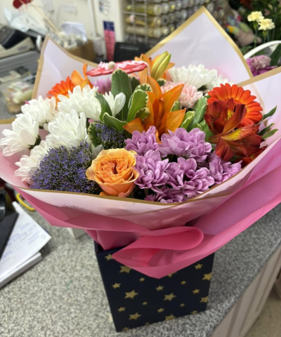 Carnival Charm - A colourful bouquet combining warm orange, soft pink, purple and crisp white tones for a bright and joyful display.