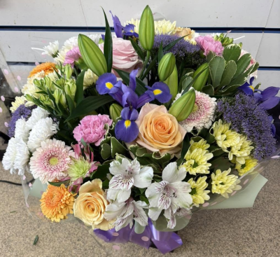 Opulent Affair - A luxurious bouquet overflowing with soft pink, peach and cream tones, accented with rich purples and abundant greenery.